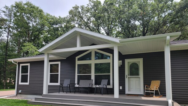 A two-story house with a covered porch, large windows, and a front door. - Beautiful new house 5 min from Sand Valley Golf and 45 min from Wisconsin Dells  (Nekoosa)