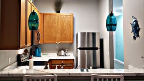 Een moderne keuken met houten kastjes, een roestvrijstalen koelkast en twee hanglampen.