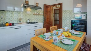 Cocina compacta con comedor, que incluye microondas, horno y una mesa de madera lista para comer.