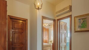 Un pasillo con puertas de madera, alfombra estampada y un candelabro.