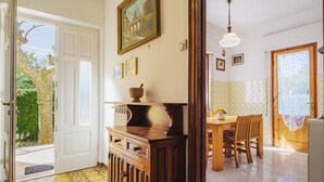 Una habitación con un armario de madera, un cuadro, una mesa de comedor con sillas y vistas al exterior.