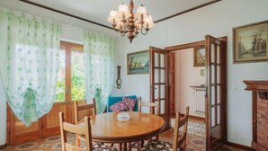 Comedor con mesa y sillas de madera, una lámpara de araña y vistas al exterior a través de una puerta.