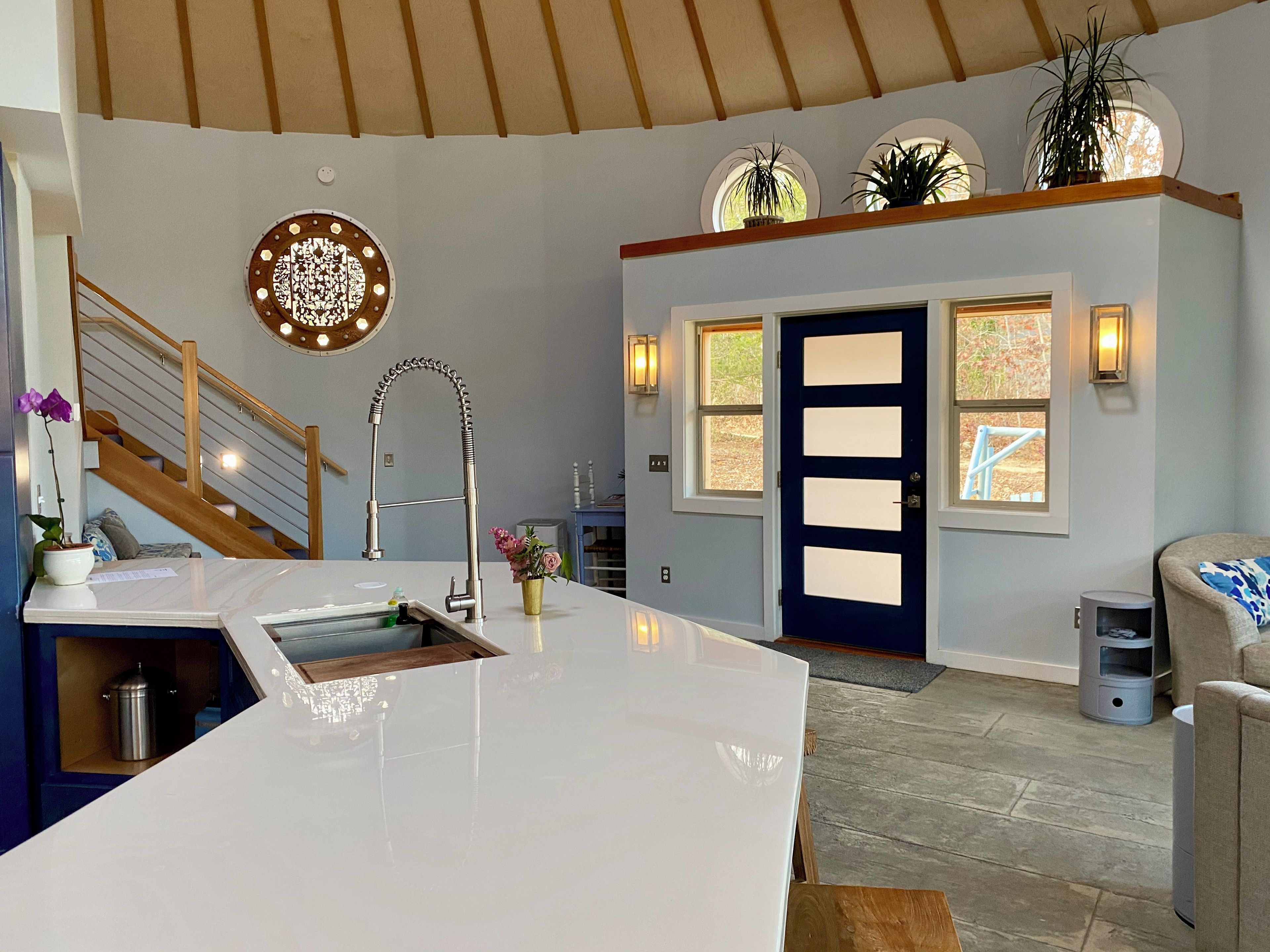 A modern kitchen with a central island, a built-in stove, and a large window.