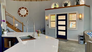 A modern kitchen with a central island, a built-in stove, and a large window.