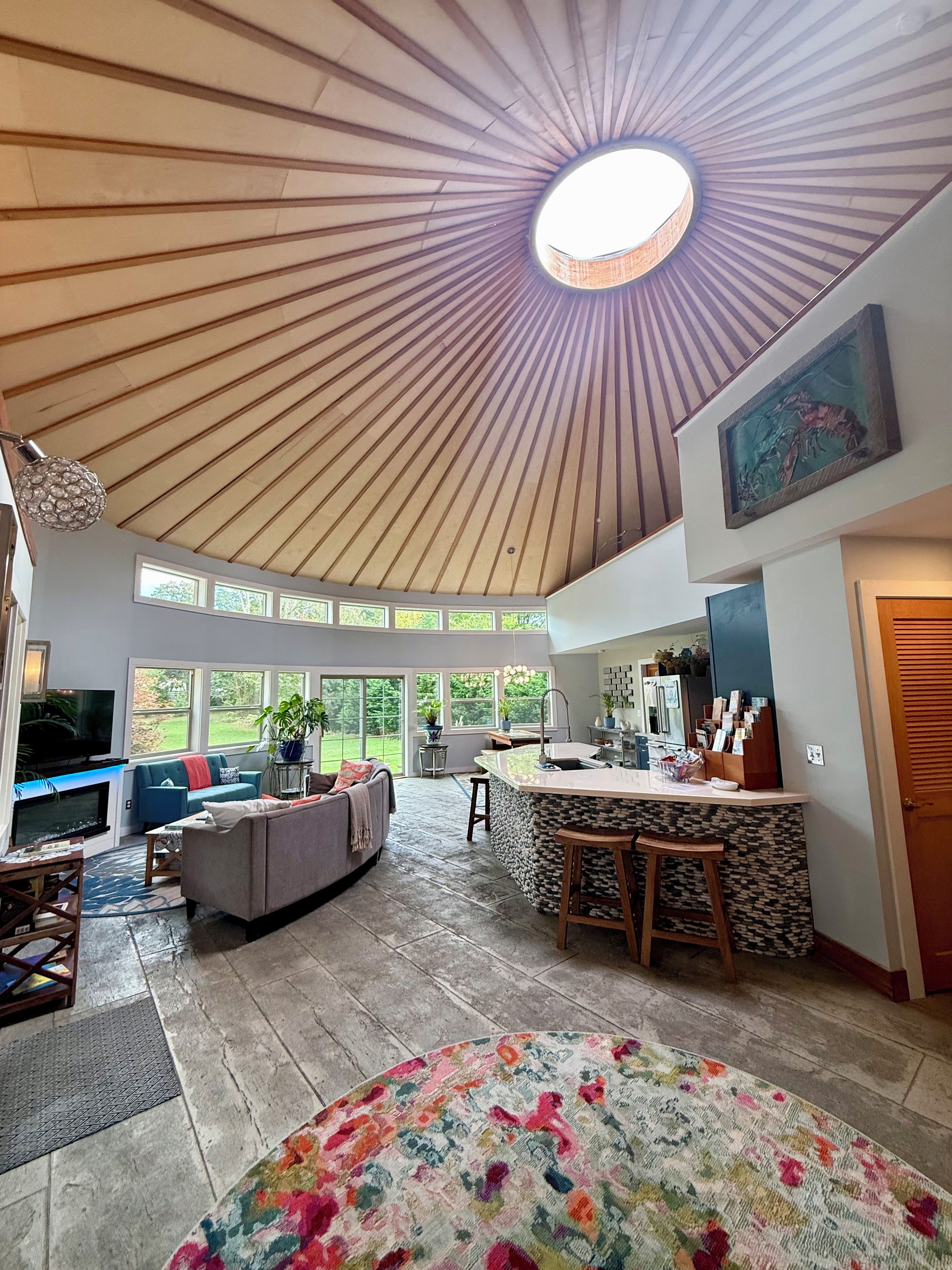 Amplia sala de estar con techo alto, televisor, sofá, mesa de centro y una zona de cocina con barra.