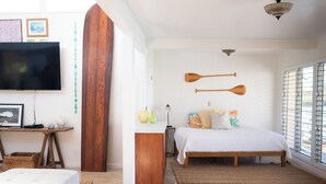 Une chambre avec un grand lit, une tête de lit en bois et deux pagaies en bois accrochées au mur.