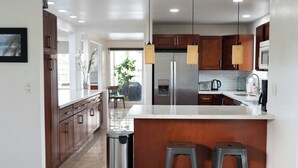 Une cuisine moderne avec des meubles en bois, un réfrigérateur en acier inoxydable et un plan de travail blanc.