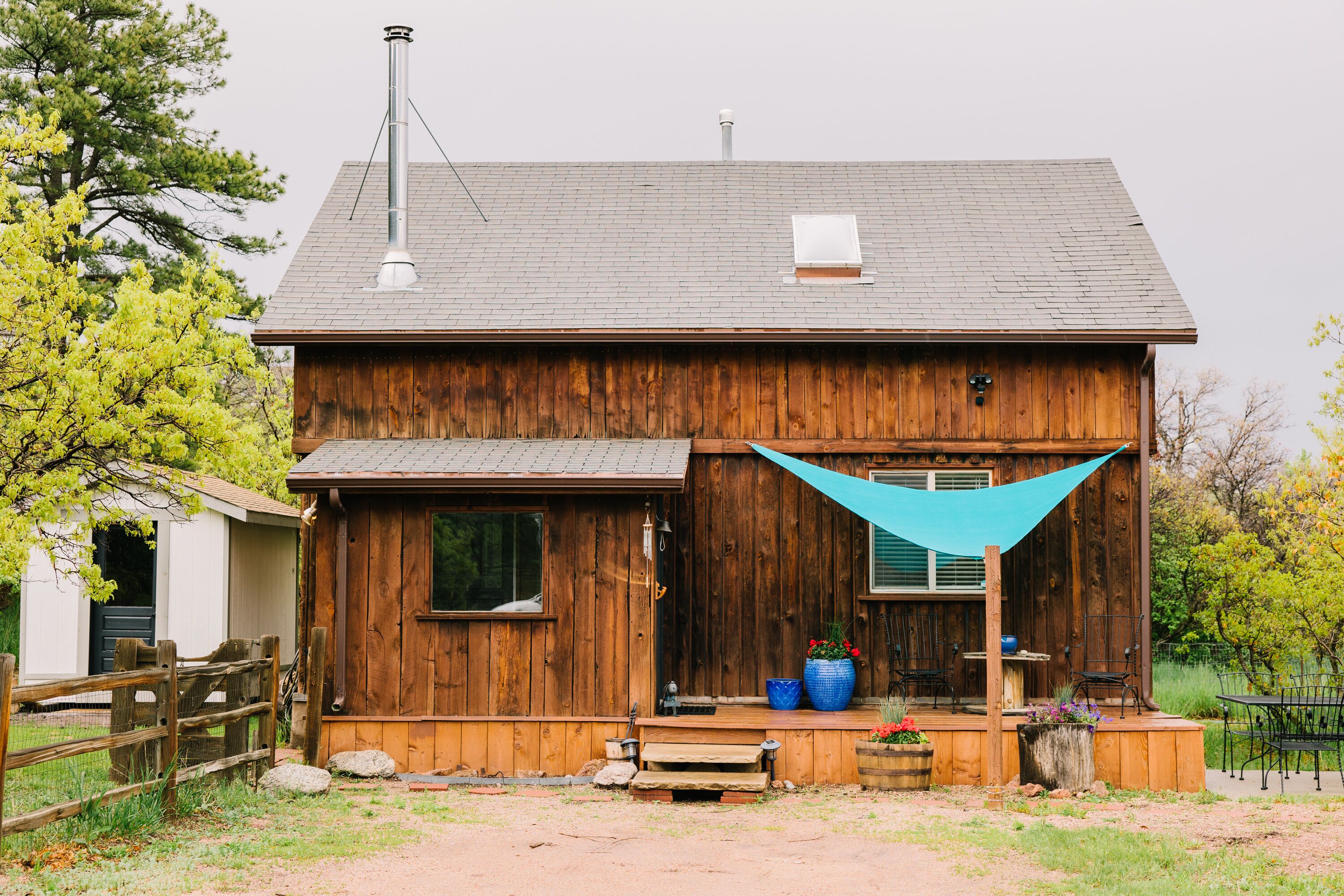 Une cabane en bois avec une véranda, une cheminée et une bâche bleue.