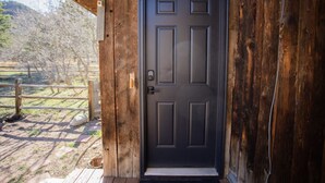 Una porta in legno con pannello nero, una maniglia in metallo e una piccola cassetta delle lettere a sinistra.