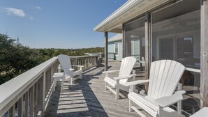 A wooden deck with white Adirondack chairs and a glass door leading to a building. - 1623 - Breakaway - Bring the Pup! Corolla Escape w/ Pool & Hot Tub (Corolla)
