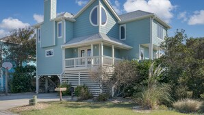 A two-story house with a balcony, a chimney, and a basketball hoop in the front yard. - 1623 - Breakaway - Bring the Pup! Corolla Escape w/ Pool & Hot Tub (Corolla)