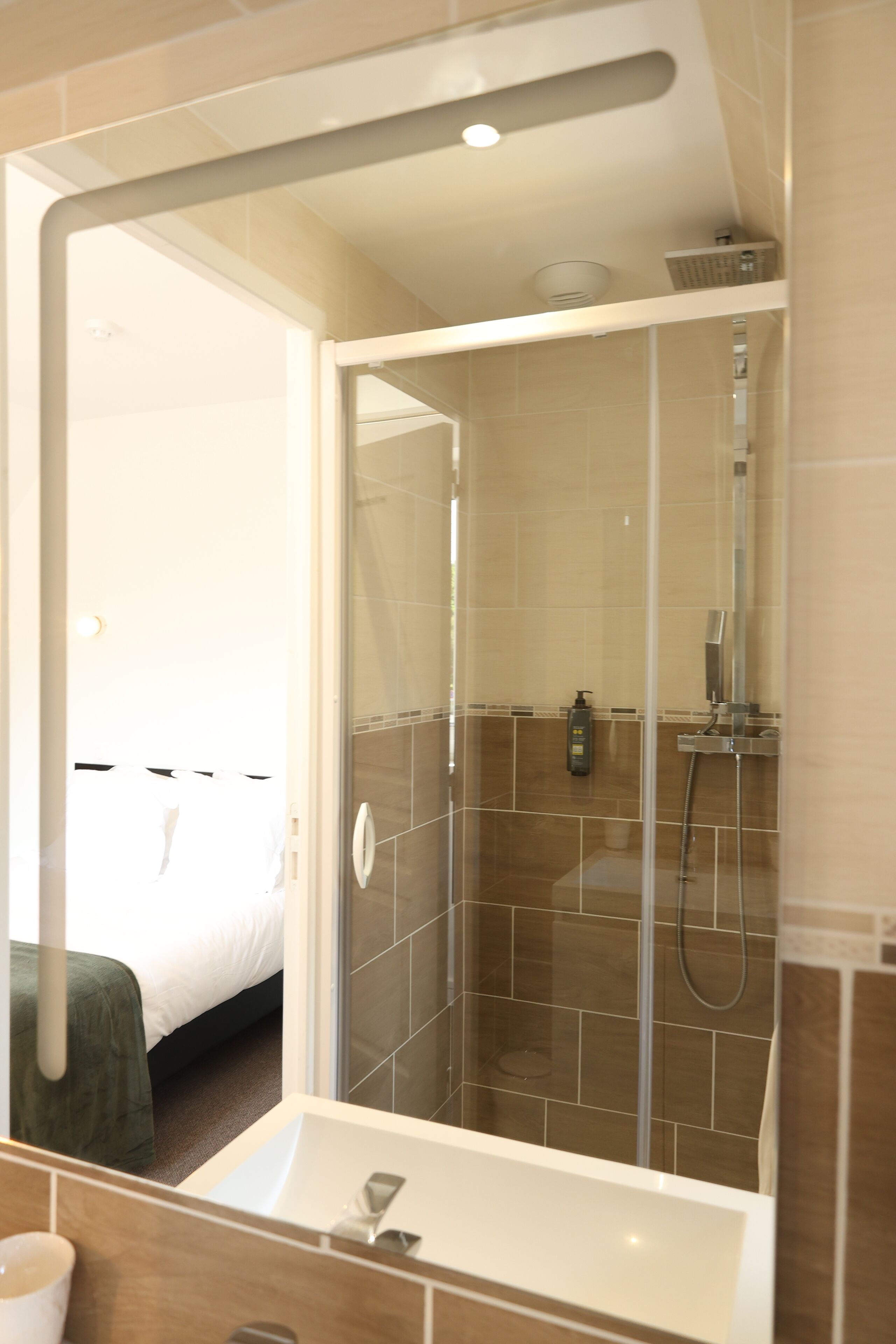 A bathroom with a glass-enclosed shower, a sink, and a mirror.