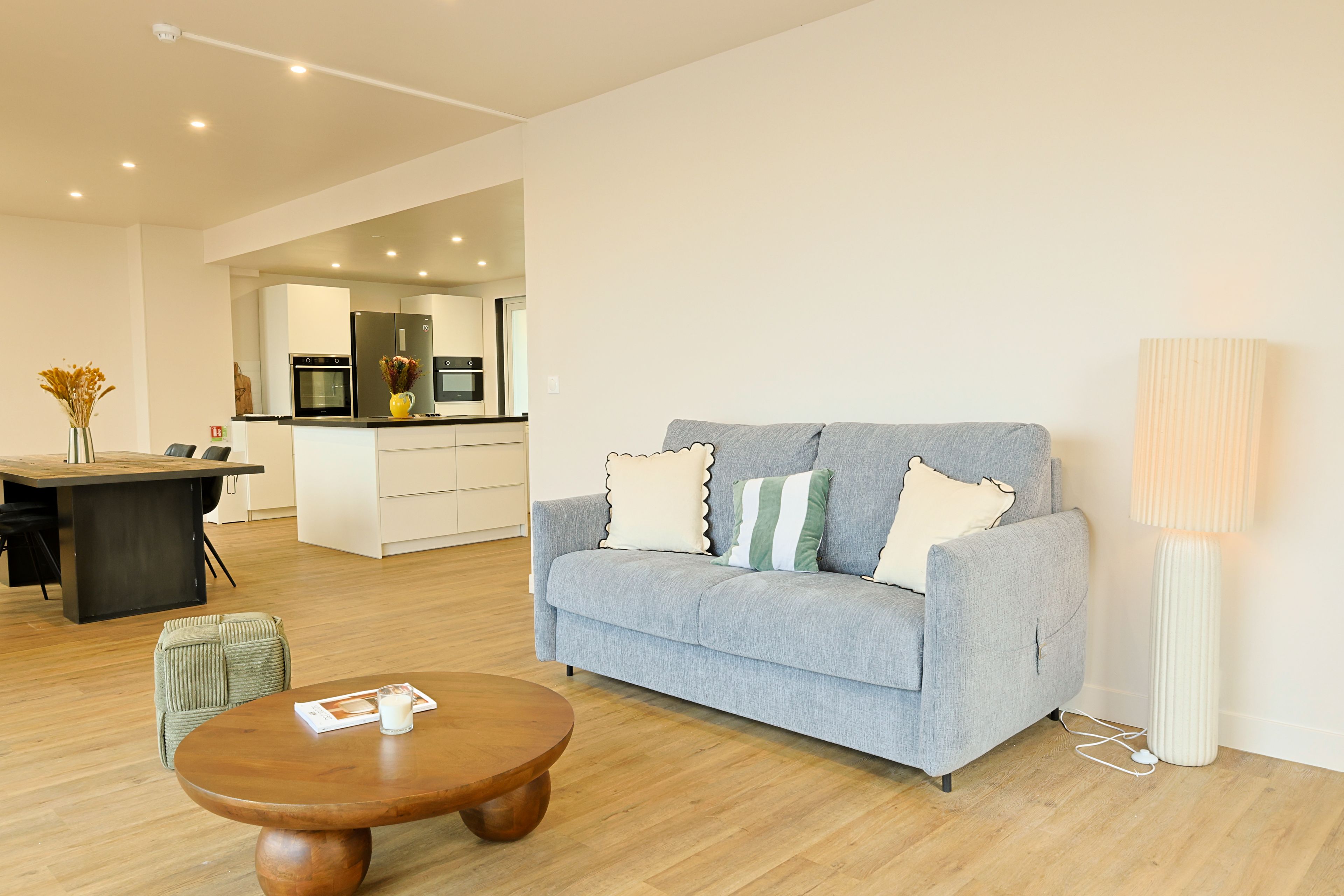 A modern living room with a grey sofa, a wooden coffee table, and a lamp.