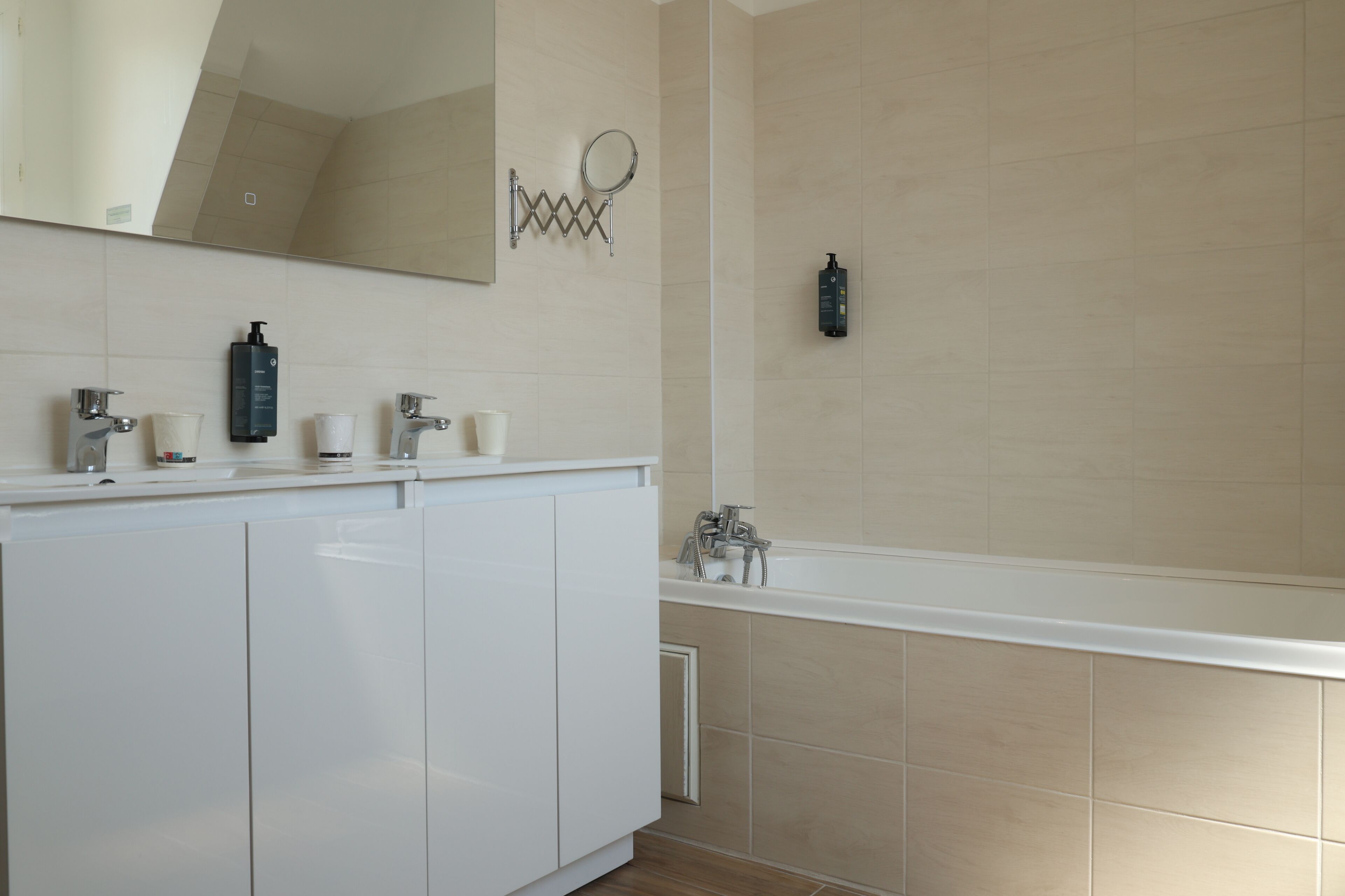 A modern bathroom with a white vanity, a large mirror, and a bathtub.