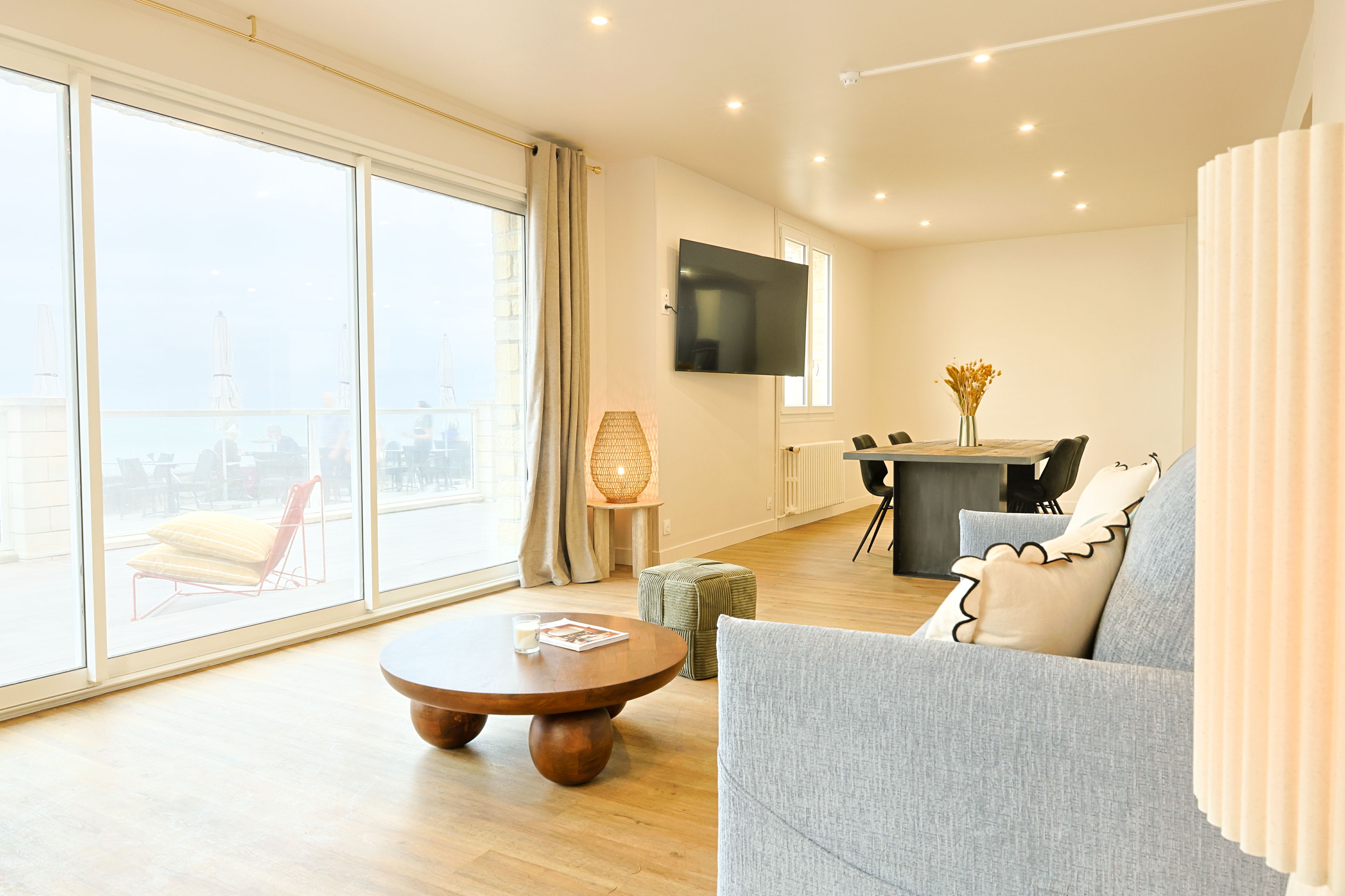 Un salon moderne comprenant un canapé, une table basse, un téléviseur et un coin repas avec des chaises et une table.