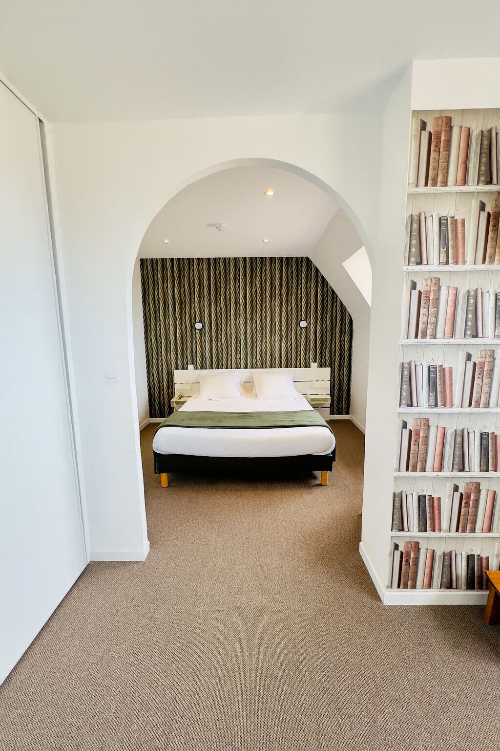 Une chambre à coucher avec un lit, une bibliothèque et un mur décoré de motifs.