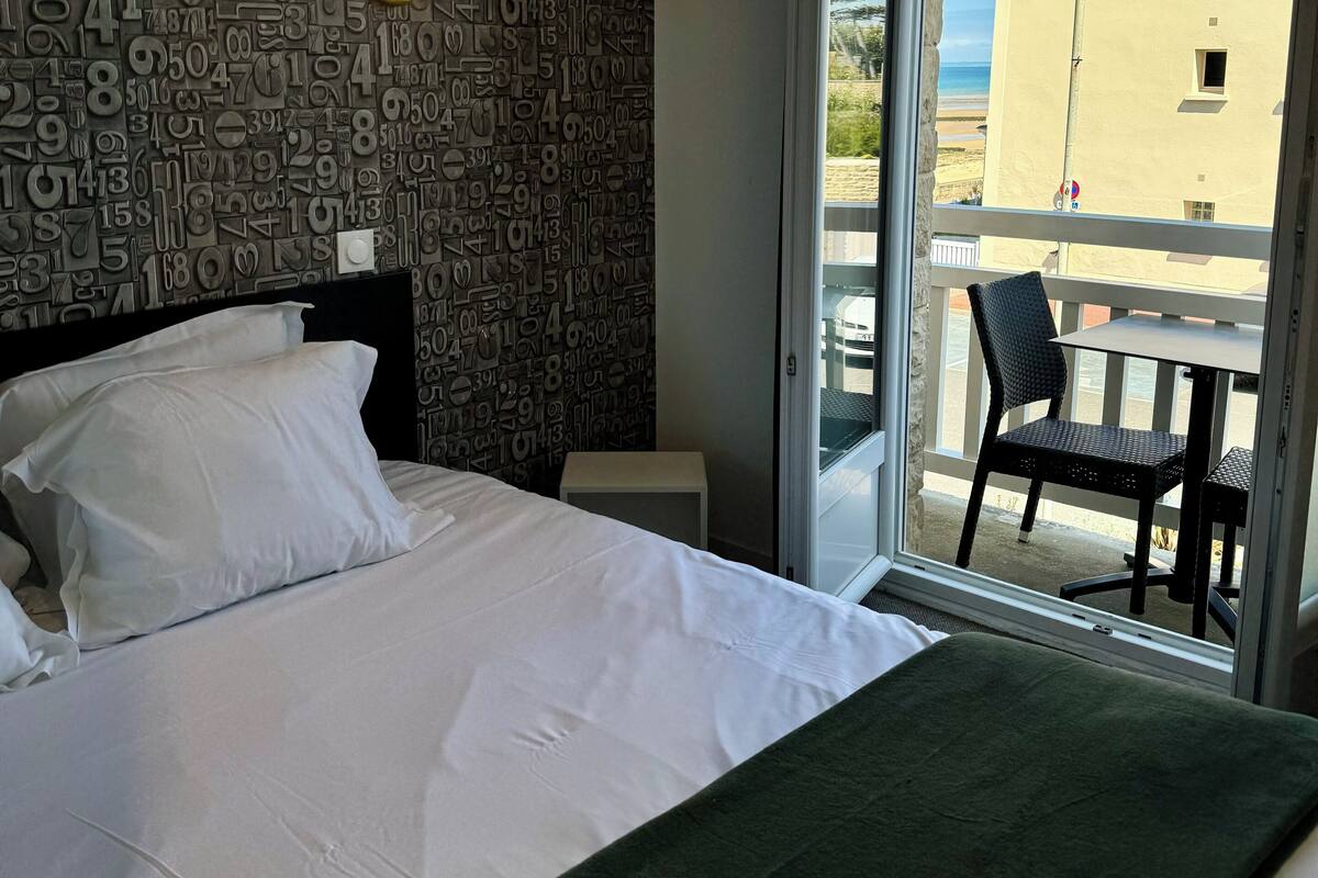 A hotel room with a bed, a view of the balcony, and a wall with numbers.