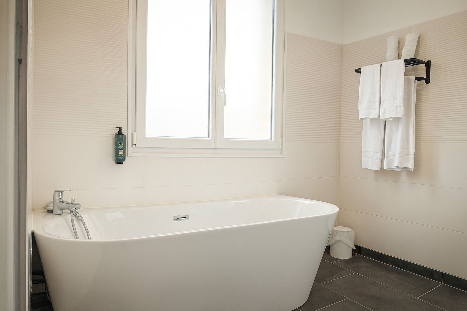 Une salle de bain moderne avec une baignoire sur pieds, une fenêtre et un porte-serviettes.