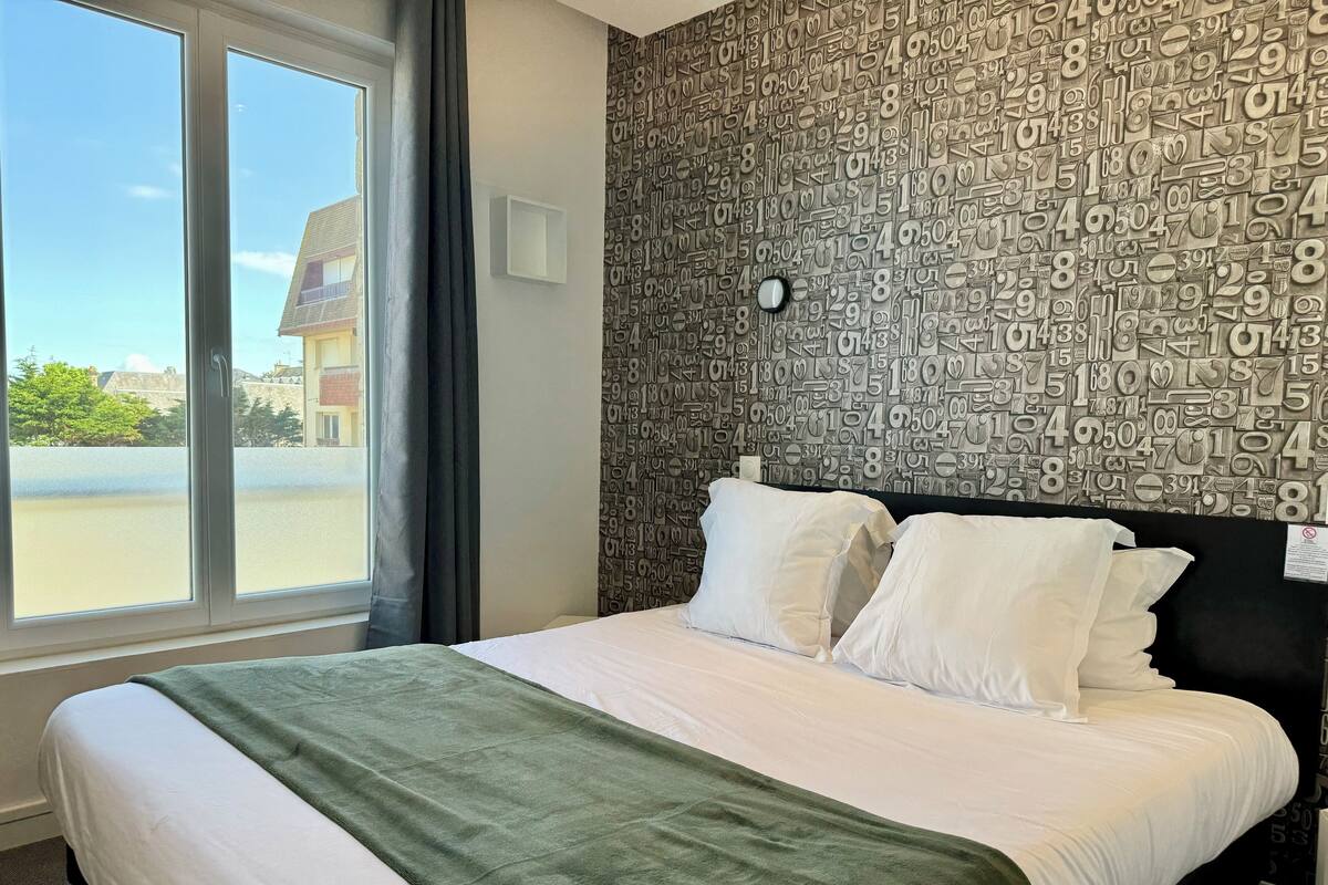 A hotel room with a large bed, a view of the outside, and a wall covered in numbers.