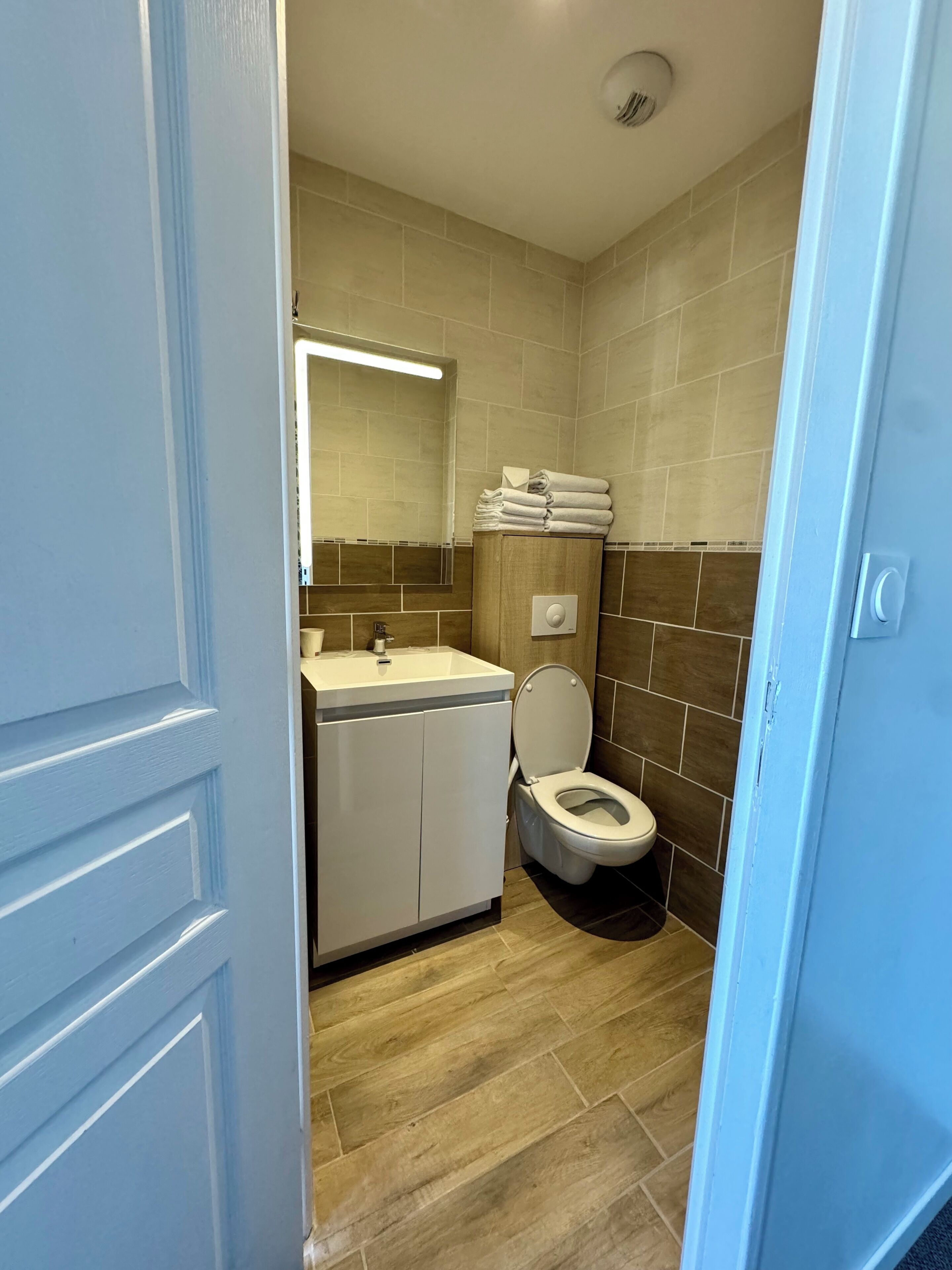 Een moderne badkamer met toilet, wastafel en opgestapelde handdoeken.