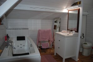 Bathroom features a large bathtub, vanity, and toilet.
