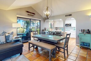 Enjoy meals and relaxation in this spacious living area with a dining table, sofa, and kitchen amenities.