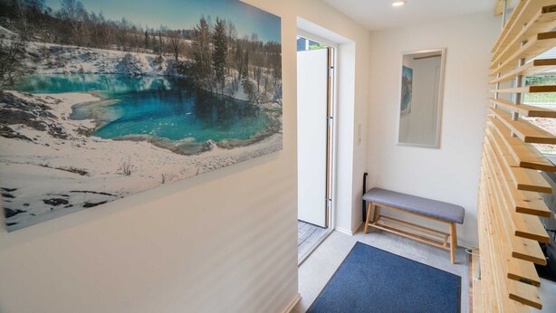 A hallway with a large painting of a winter landscape, a bench, and a wooden bench area. - Ferienhaus Harzblüte (Blankenburg (Harz))