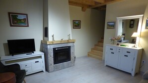 Un salon doté d’une cheminée, d’un téléviseur et d’un escalier menant à un autre niveau.