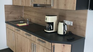 Eine moderne Küche mit Holzausstattung, einer schwarzen Arbeitsplatte, einer Kaffeemaschine und einem Wasserkocher.