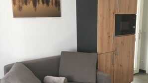 Ein modernes Wohnzimmer mit einem grauen Sofa, einer Holzkommode und einem an der Wand befestigten Kunstwerk.