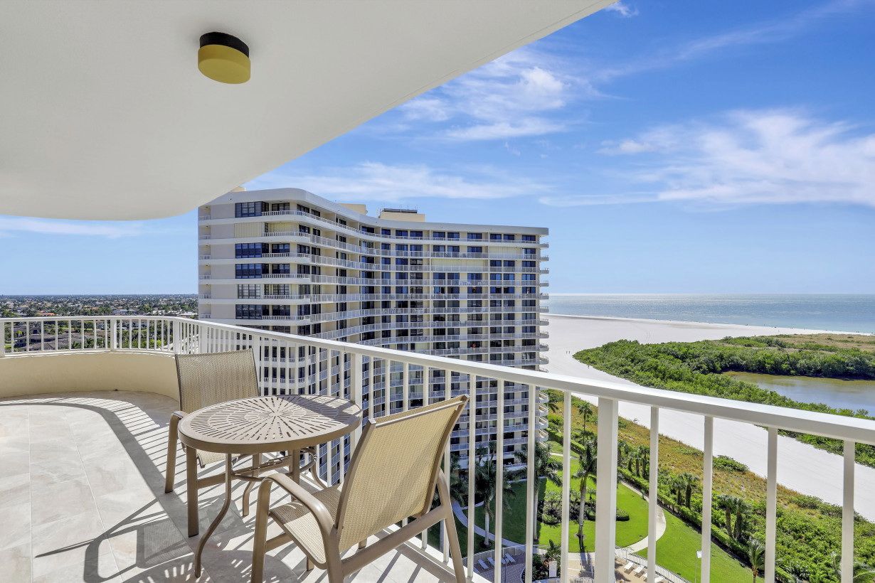 A balcony with a view of a high-rise building, a river, and a green landscape.