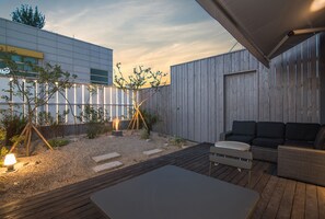 An outdoor patio area with a modern design, including a seating area with a sofa and a table, surrounded by a wooden deck and gravel. - Blo By Blo Hotel (Daegu)