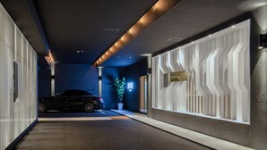 Un pasillo moderno y bien iluminado, con un coche estacionado al fondo, una planta en maceta y un diseño de pared original.