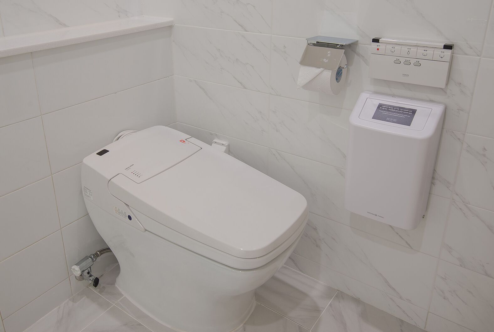 A modern bathroom with a toilet, a wall-mounted bidet, and a water heater.