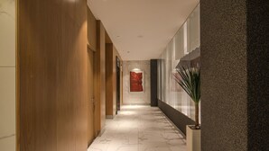 Un pasillo moderno con paneles de madera, suelo de mármol y una gran obra de arte roja en la pared.