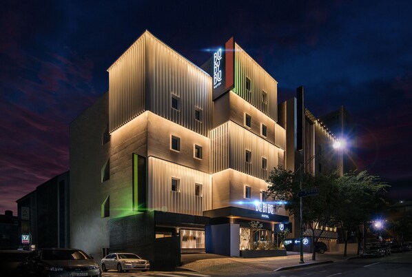 A multi-story hotel with a modern design, featuring a prominent sign and a parking area. - Blo By Blo Hotel (Daegu)