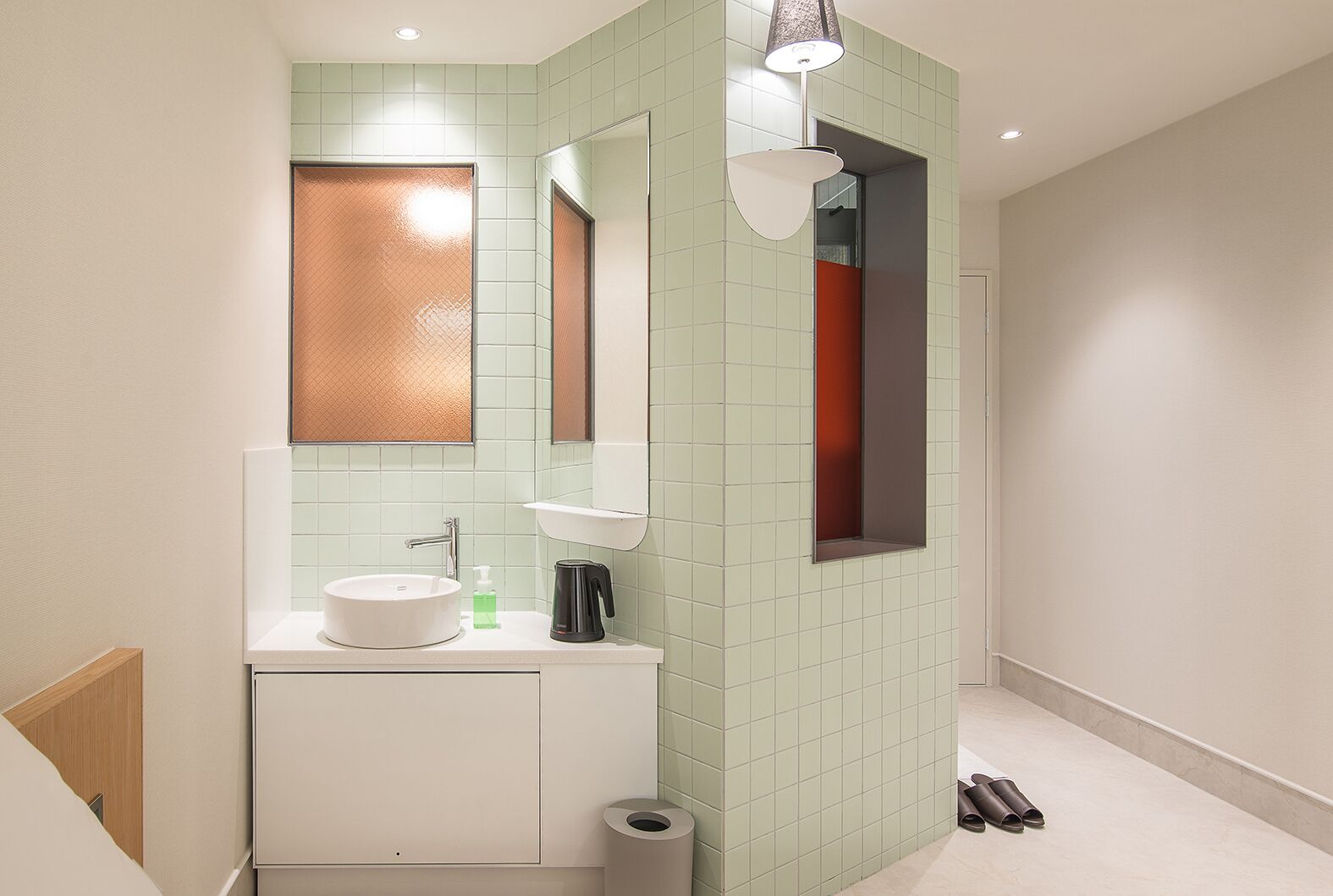Un baño moderno con un lavabo blanco, un espejo, un perchero para toallas y un inodoro.