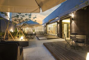 An outdoor patio area with wooden flooring, tables, chairs, and umbrellas. - Blo By Blo Hotel (Daegu)
