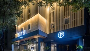 Un hotel con diseño moderno, que destaca un letrero grande con la palabra 'HOTEL' y un símbolo de 'P' para estacionamiento.