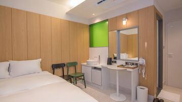 Una habitación de hotel moderna con una cama grande, un escritorio con lavabo, un espejo y una pared de acento verde.