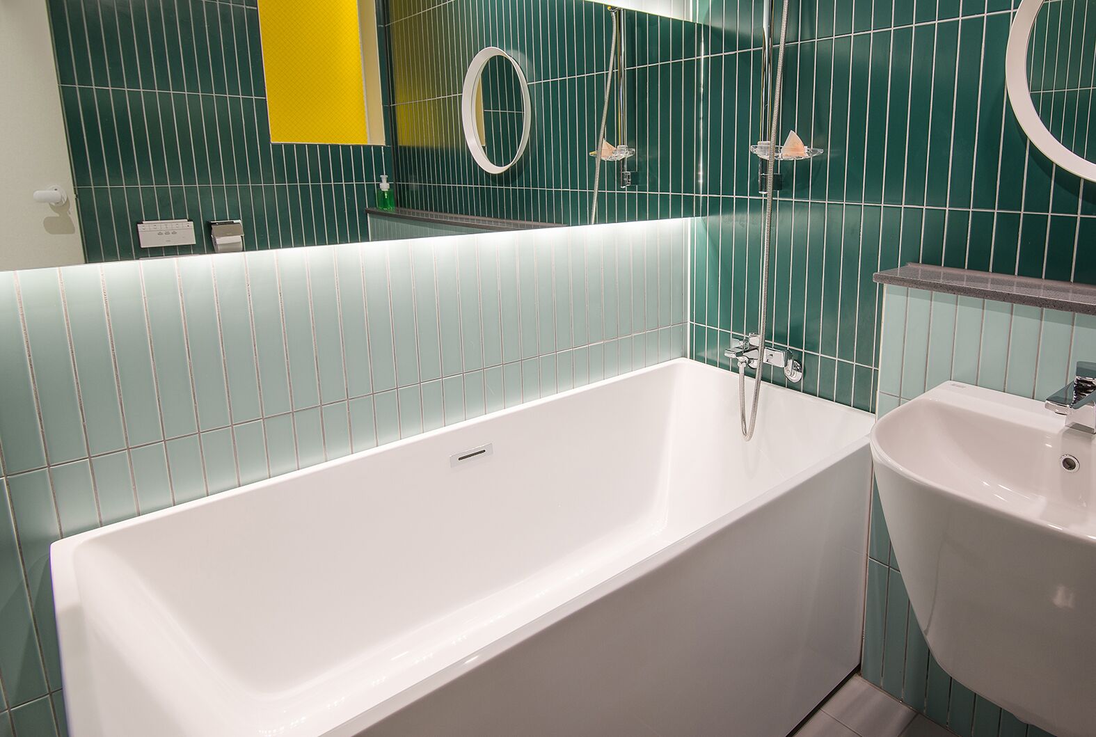 A modern bathroom with a white bathtub, a sink, and a mirror.