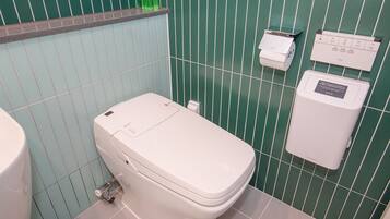 Un baño con inodoro, secamanos automático y dispensador de toallas de papel.