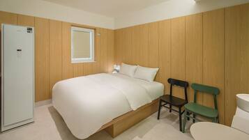 A bedroom with a bed, a wooden wardrobe, a window, a chair, and a toilet.