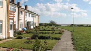A residential area with terraced houses, a pathway, and a view of the sea. - 5 Sea View Walk - comfortable family home right on the beach, free parking, pets (Pakefield)