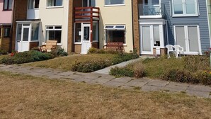 A row of terraced houses with front gardens, a clear sky, and a street lamp. - 5 Sea View Walk - comfortable family home right on the beach, free parking, pets (Pakefield)