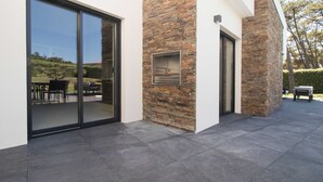 A modern house with a stone facade, large sliding glass doors, and a patio area.