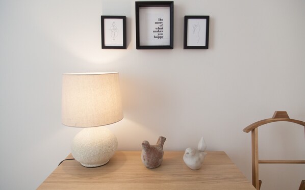 A room with a table, a lamp, and three framed artworks on the wall.