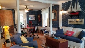 Un salon chaleureux avec un canapé bleu, une table basse et un coin repas comprenant une table et des chaises.