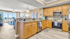 A modern kitchen with wooden cabinets, granite countertops, stainless steel appliances, and a view to the outside. - WHERE THE GULF MEETS YOUR LIVING ROOM! (Ft Walton Beach)