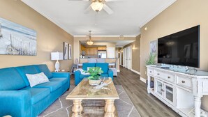 A living room with a blue sofa, a coffee table, and a TV on a white cabinet. - WHERE THE GULF MEETS YOUR LIVING ROOM! (Ft Walton Beach)
